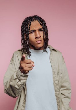 Pembe arka planda öne doğru örülmüş saçları olan genç bir adam..