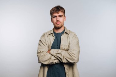 Gri arka planda kollarını çapraz yapmış genç bir adam..