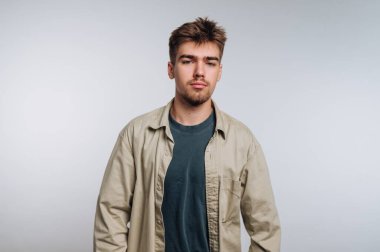 Sade bir arka planda sıradan giyinmiş genç bir adam..