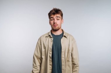 Sıradan giyinmiş genç bir adam arka planda dikiliyor..