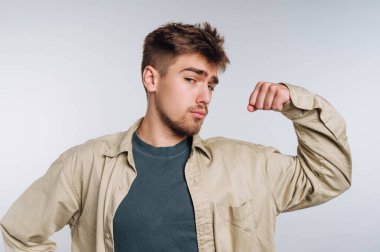 Sıradan giyinmiş genç bir adam kolunu esnetiyor, kendine güvenen bir duruşu var..