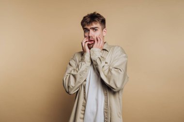 Bej arka plana karşı şaşırmış genç bir adam.