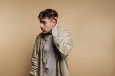 Gündelik giysiler içinde genç bir adam, kulaktan kulağa dinliyor.