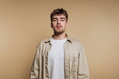 Bej arka plana karşı sıradan tarzı olan genç bir adam..