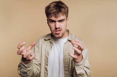 Kızgın bir ifadesi olan ve ellerini kaldıran genç bir adam..