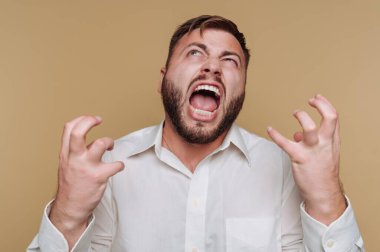 Beyaz gömlekli adam bej arka planda hayal kırıklığı yaşıyor.