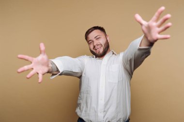 Beyaz gömlekli gülümseyen adam kollarını açmış uzanıyor..