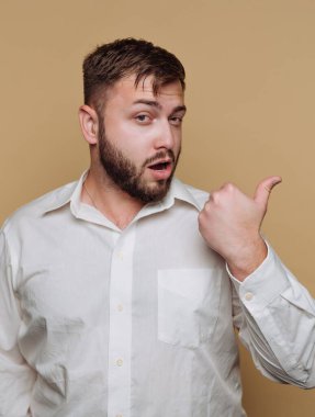 Beyaz gömlekli, başparmağı ve bej arkaplanı olan bir adam..