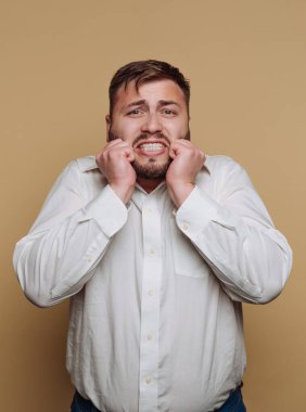 Beyaz gömlekli adam bej arka planda hayal kırıklığı yaşıyor.