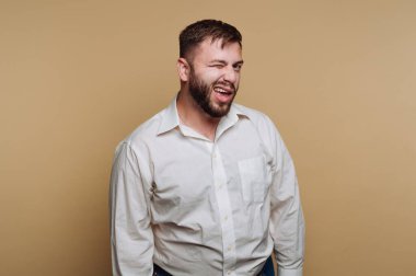 Beyaz gömlekli adam bej arka planda göz kırpıyor..