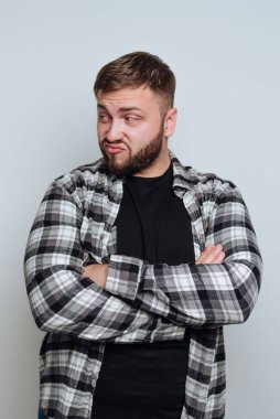 Ekose gömlekli, kolları çaprazlanmış, şüpheli görünen bir adam..