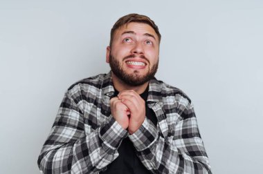 Ekose gömlekli adam umut dolu bir ifadeyle yukarı bakıyor..