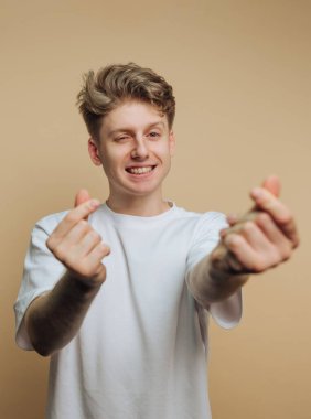 Beyaz tişörtlü genç adam kalp hareketi yapıyor..