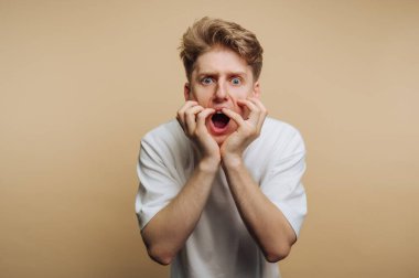 Bej arka plana karşı şaşırmış genç bir adam..