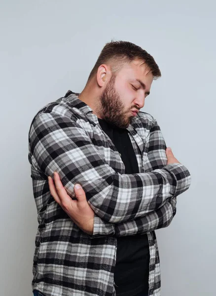 Kolları çapraz ekose gömlekli adam, düşünceli görünüyor..