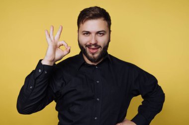 Sarı bir duvarın önünde duran bir adam sağ eliyle 