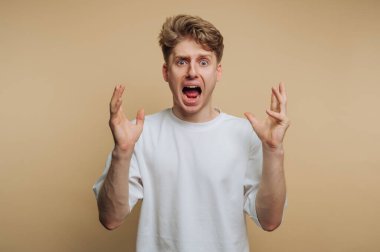 Sade bir geçmişi olan genç bir adam stüdyoda duruyor. Açık kahverengi saçları var ve elleri havada bağırıyor. Yüzünde şaşkınlık ve heyecan var..