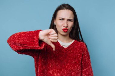 Kırmızı kazaklı kadın hoşnutsuz bir ifadeyle baş parmağını kaldırıyor..