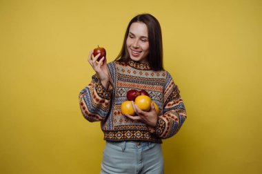 Sarı arka planda elma tutan kadın.