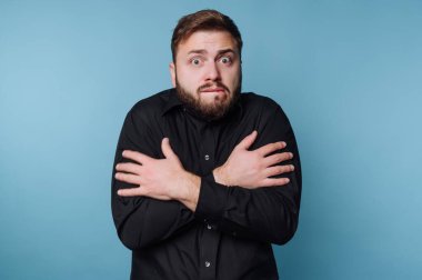 Siyah gömlekli adam göğsünde çapraz kollarla kafası karışmış görünüyor..