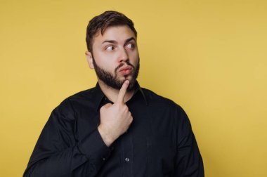 Siyah gömlekli adam sarı arka planı düşünüyor..