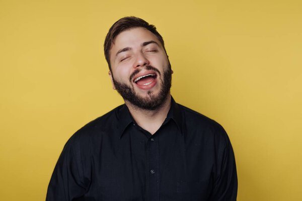 Man in black shirt laughing against yellow background