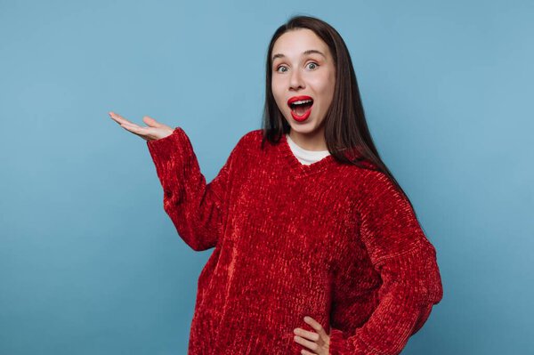 Woman in red sweater gesturing with excitement against blue background.