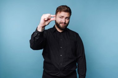 Siyah gömlekli bir adam, küçük beden ve mavi arka planda parmakları var..