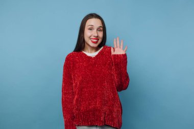 Kırmızı kazaklı, gülümseyen kadın mavi arka planda sallanıyor..