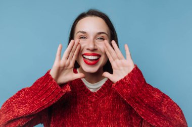 Smiling woman in red sweater shouting with hands around mouth