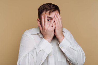 Sade bir geçmişi olan bir odada duran bir adam. Suratını elleriyle kapatıyor ve bir sürpriz reaksiyonu gösteriyor. Odadaki ışık parlak..