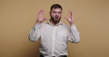 Açık renkli gömlekli bir adam duygularını açıkça göstermek için ellerini kullanır. Sade bir arka planı olan bir stüdyoda ve izleyiciyi doğrudan ifadelerle meşgul ediyor..