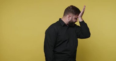 Bir adam hayal kırıklığını elini alnına koyarak gösterir. O, parlak sarı bir arka planı olan bir stüdyoda. Vücut dili bir yenilgi hissi veriyor..