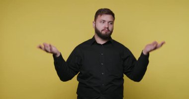 Bir adam sarı arka planda duruyor. Fikirlerini ya da duygularını ifade etmek için ellerini kaldırır. Bu stüdyo ortamında yapılan bir iletişim egzersizinin bir parçası..