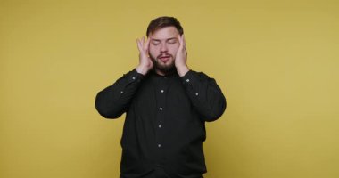 Bir kişi sarı bir duvara karşı duruyor, iki eliyle başını tutuyor. Bu iç mekan ortamında hayal kırıklıklarını ve stresi ifade ediyorlar..