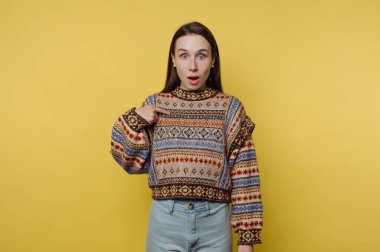 Sarı arka planda kendini gösteren desenli süveterli bir kadın..