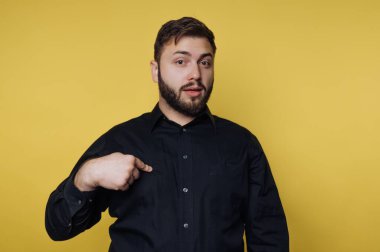 Siyah gömlekli adam sarı arka planda kendini gösteriyor.