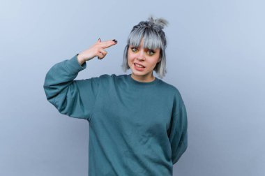 Gri saçlı genç bir kadın eliyle silah hareketi yapıyor..