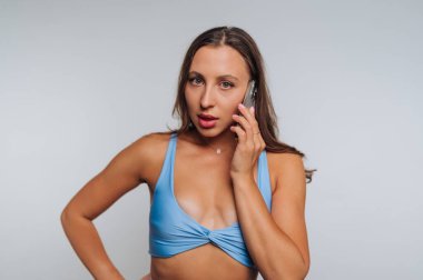 Mavi spor sutyenli bir kadın akıllı telefondan konuşuyor..
