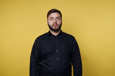 Sarı arka planda siyah gömlekli, şaşırmış bir adam..