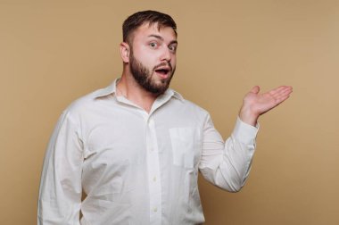 Beyaz gömlekli adam bej arka planda sürpriz hareketler yapıyor..