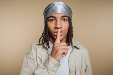 Parmakları dudaklarında genç bir adam sessizce işaret veriyor, durag takıyor..