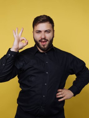 Siyah gömlekli adam sarı arka plana karşı iyi bir hareket yapıyor..