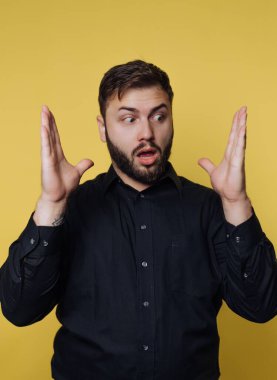 Siyah gömlekli adam sarı arka planda sürpriz yapıyor..