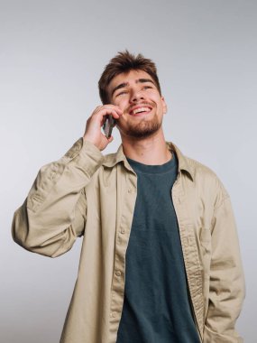 Genç adam akıllı telefonda konuşurken gülüyor..