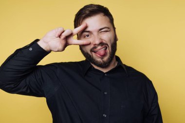 Man in black shirt making a playful face against yellow background.