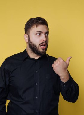 Siyah gömlekli adam sarı arkaplanı işaret ediyor..