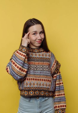 Sarı arka planda desenli süveter giyen genç bir kadın..