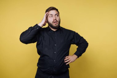 Adam parlak sarı bir arka plana karşı duruyor düşünceli bir ifadeyle. Onun kafasında bir eli ve kalçasında bir eli var. Şaşırmış ya da kafası karışmış görünüyor..