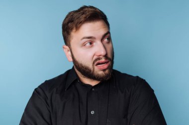 Sakallı bir adam beklenmedik haberlere şaşırır. Gözleri kocaman ve ağzı hafifçe açık..